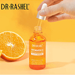 A bottle of Dr Rashel Vitamin C Serum with a dropper applicator and Orange in Background
